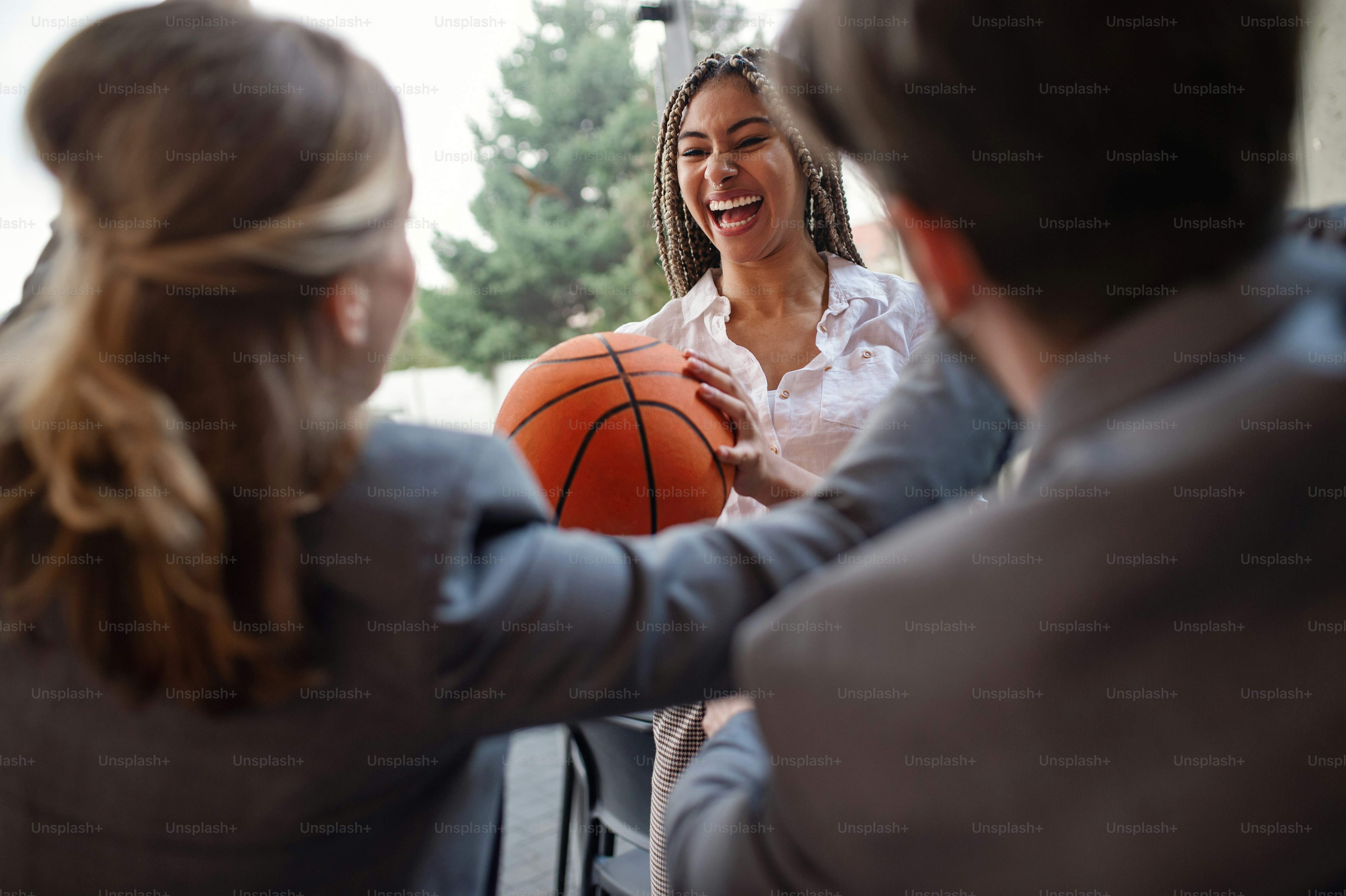 Un grupo de jóvenes empresarios alegres jugando baloncesto en la oficina, tomando un concepto de descanso.