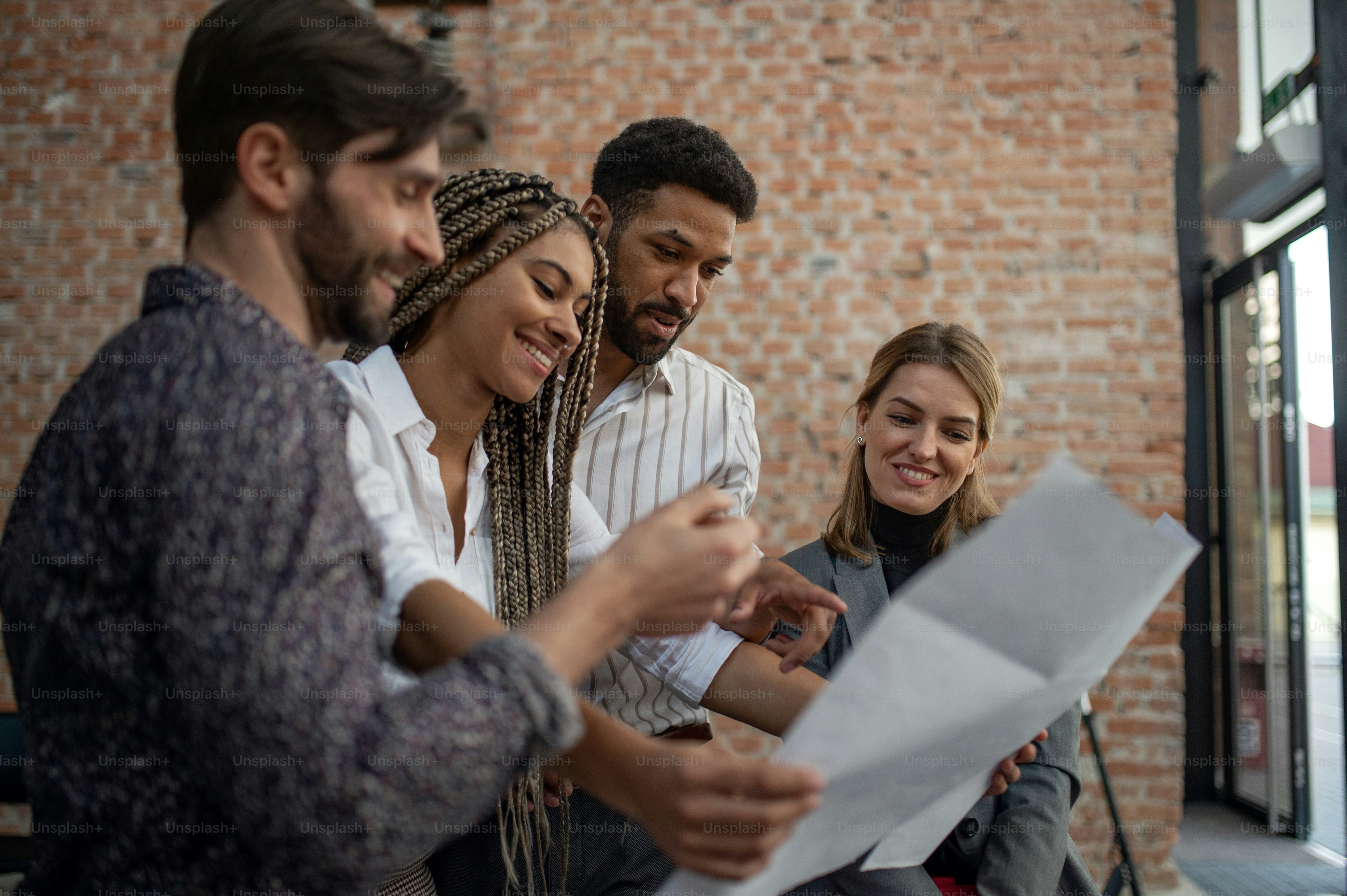 Jóvenes empresarios alegres de pie y trabajando en la oficina, un concepto de cooperación y lluvia de ideas.
