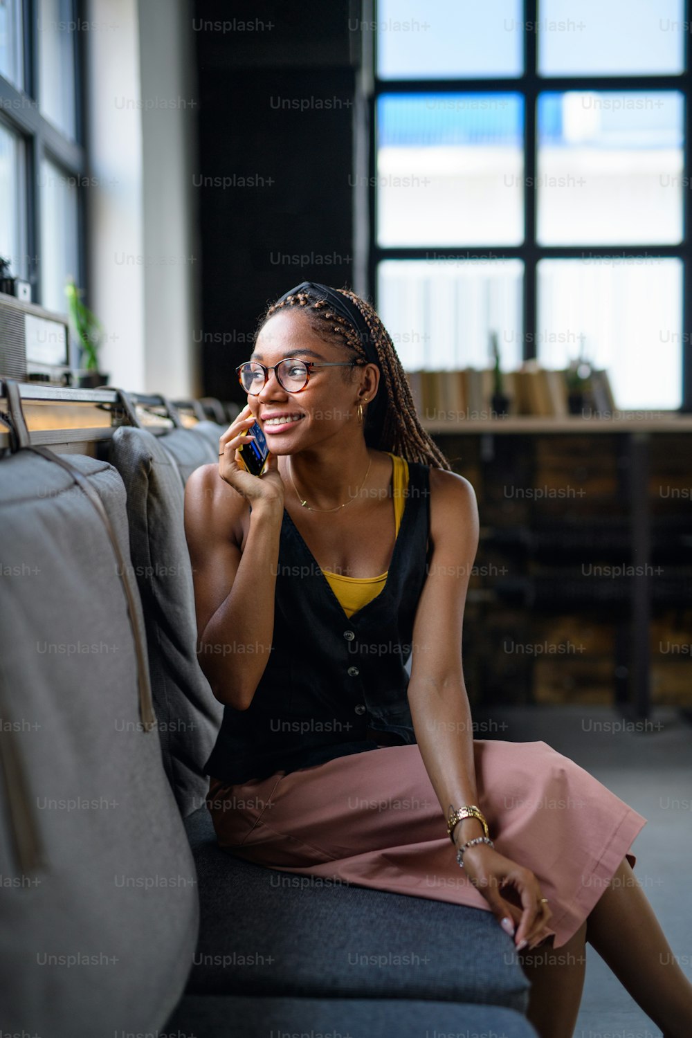 Portrait of young african-american business woman indoors in office, using smartphone.