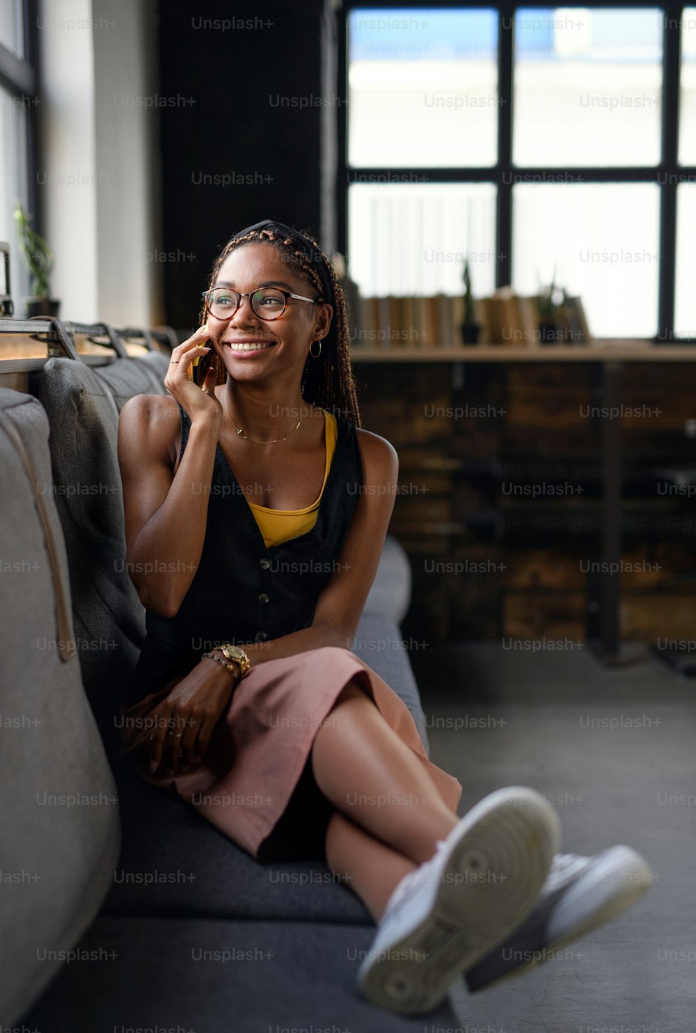 Portrait of young african-american business woman indoors in office, using smartphone.