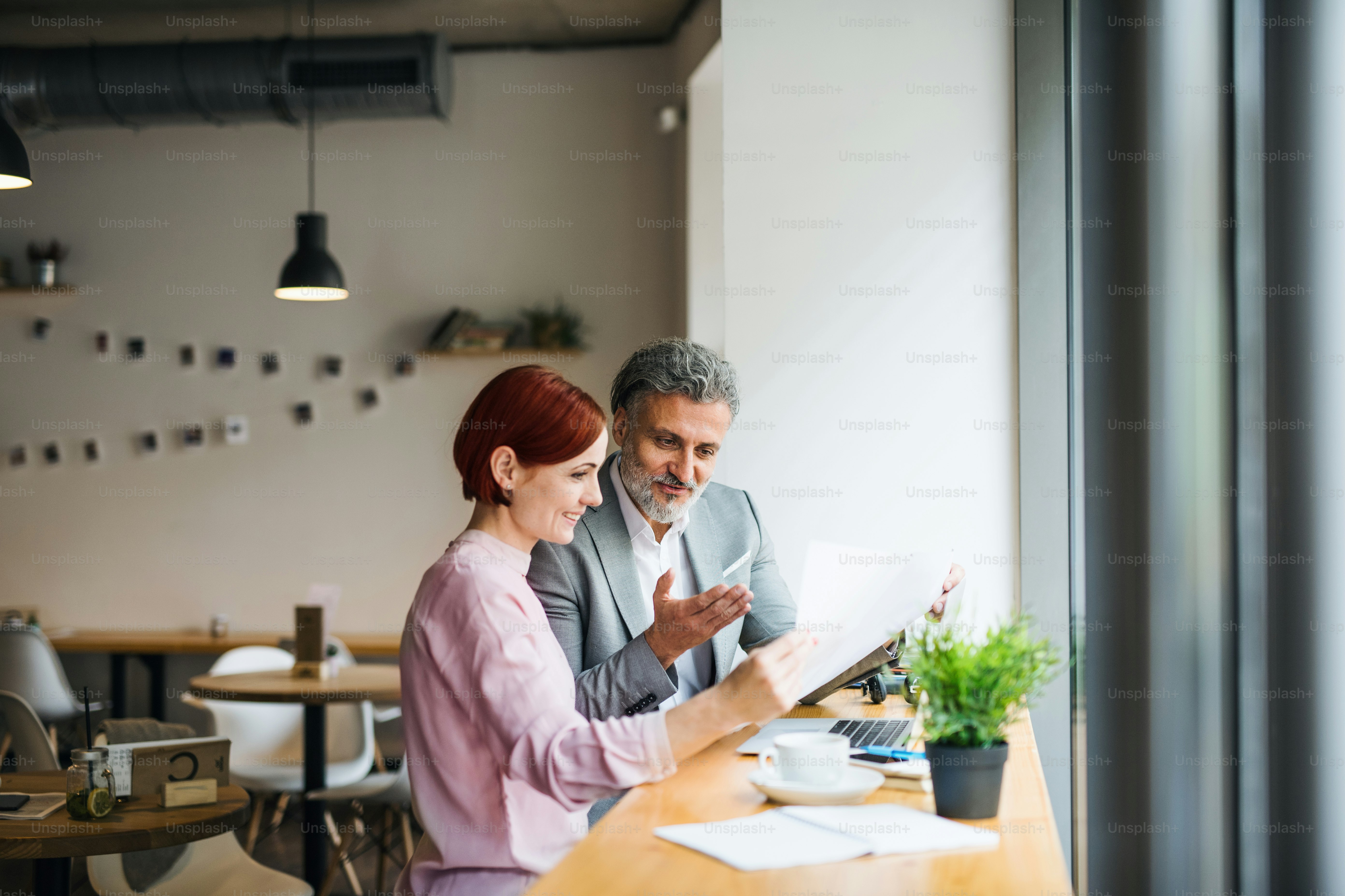 A man and woman having business meeting in a cafe, using laptop. photo ...