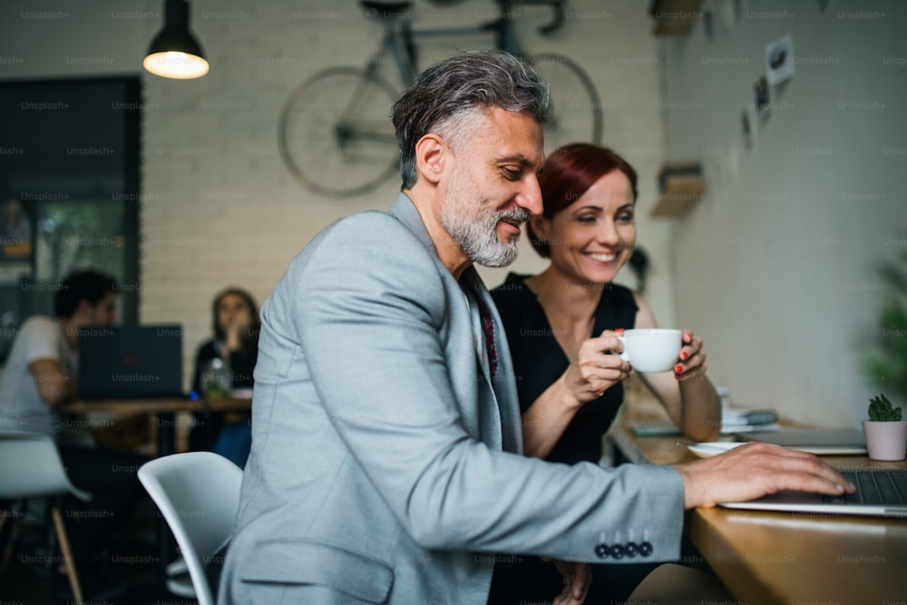 Um homem e uma mulher tendo reunião de negócios em um café, usando laptop.