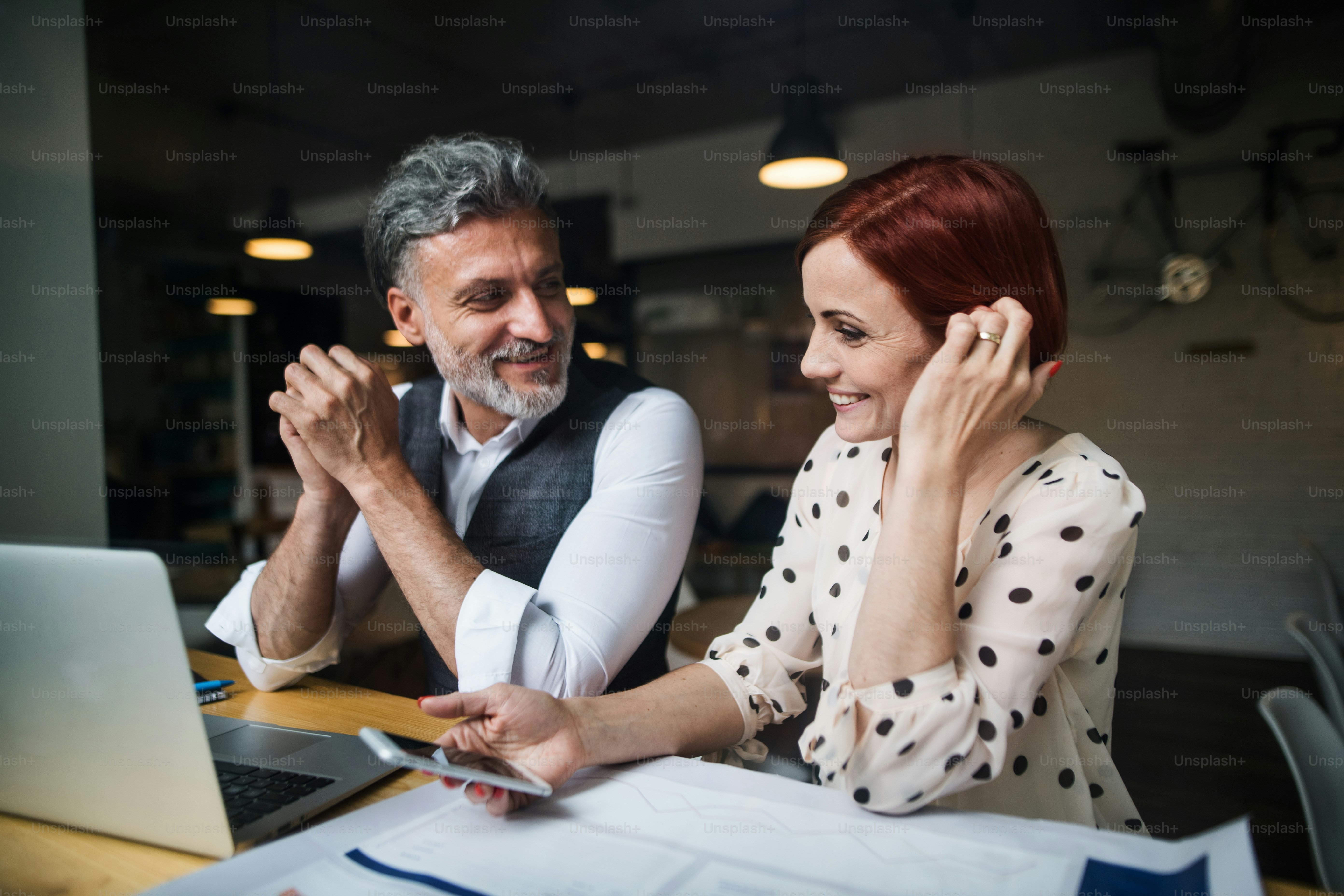 A man and woman having business meeting in a cafe, using laptop and smartphone.