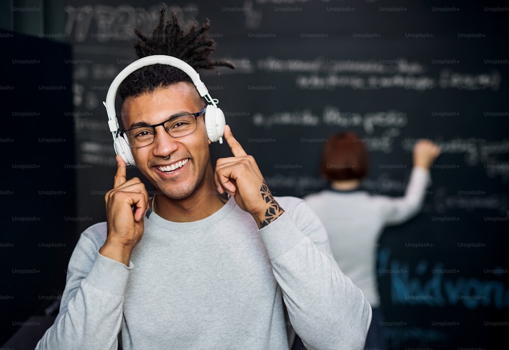 A young businessman with headphones in office, listening to music.