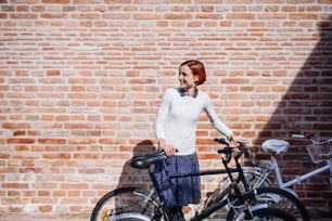 A portrait of young business woman with bicycle standing outdoors. Copy space.
