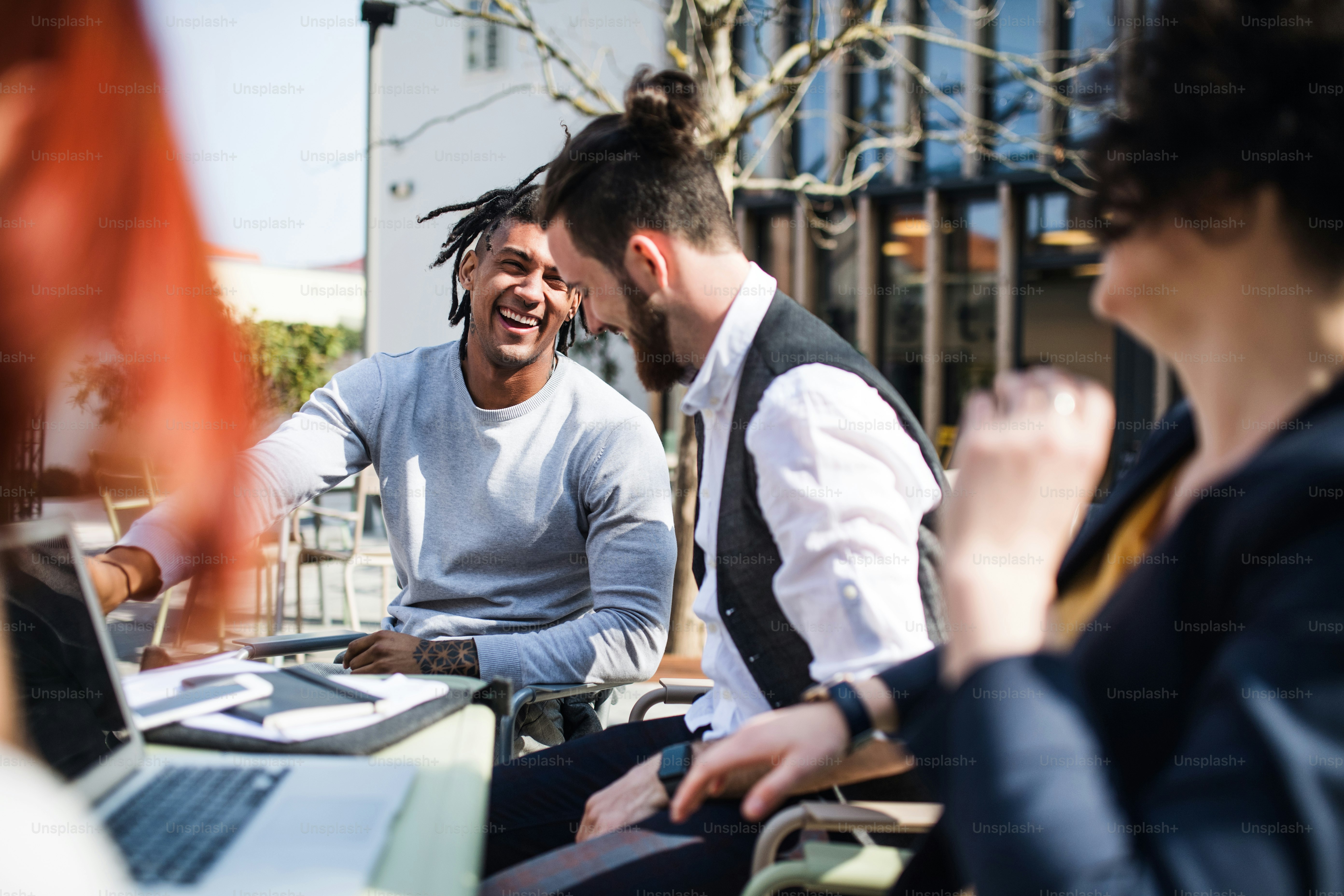 Young businesspeople with laptop outdoors in courtyard, laughing. Start-up concept