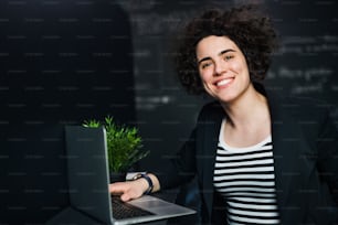 Una joven empresaria con computadora portátil en la oficina, trabajando.