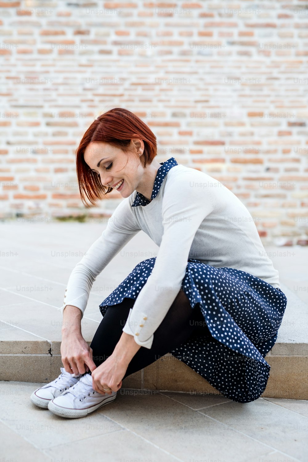 Un ritratto di giovane donna d'affari seduta all'aperto, che si lega i lacci delle scarpe. Concetto di start-up.