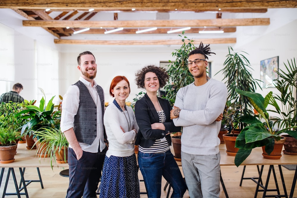 Portrait of group of young businesspeople standing in office, looking at camera.