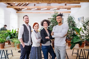 Portrait of group of young businesspeople standing in office, looking at camera.