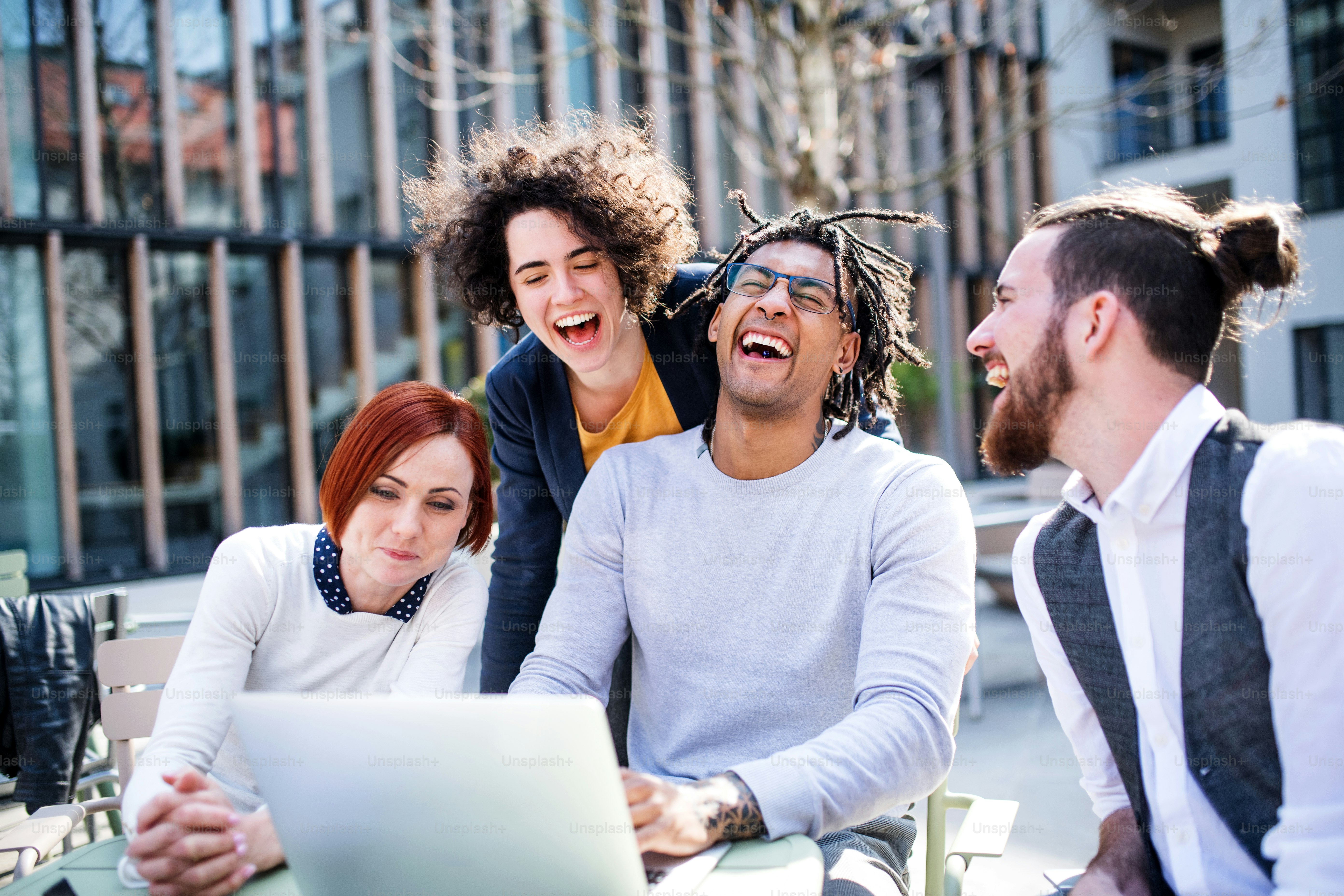 Jovens empresários com laptop ao ar livre no pátio, rindo. Conceito de start-up