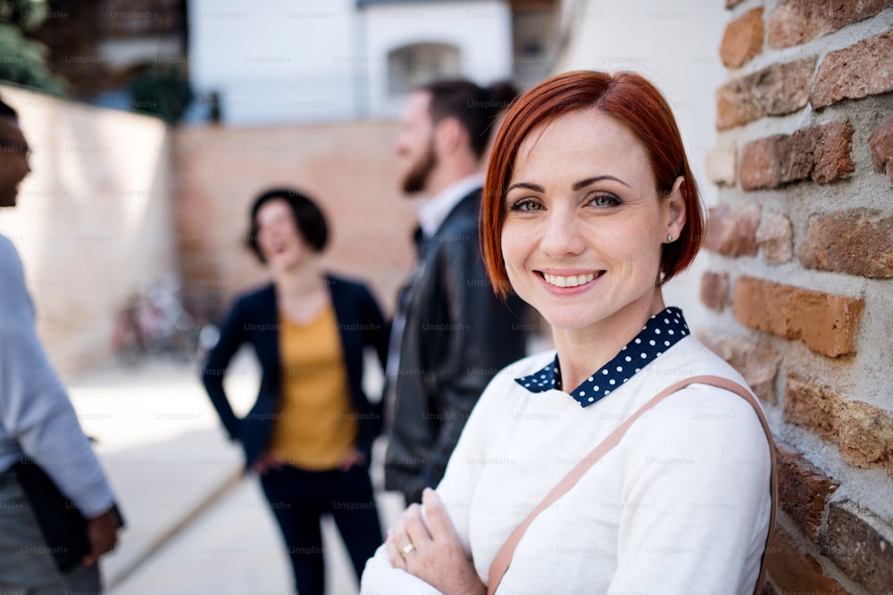 Um retrato de uma jovem empresária com colegas em pé ao ar livre. Espaço de cópia. Conceito de start-up.