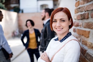 A portrait of young business woman with colleagues standing outdoors. Copy space. Start-up concept.