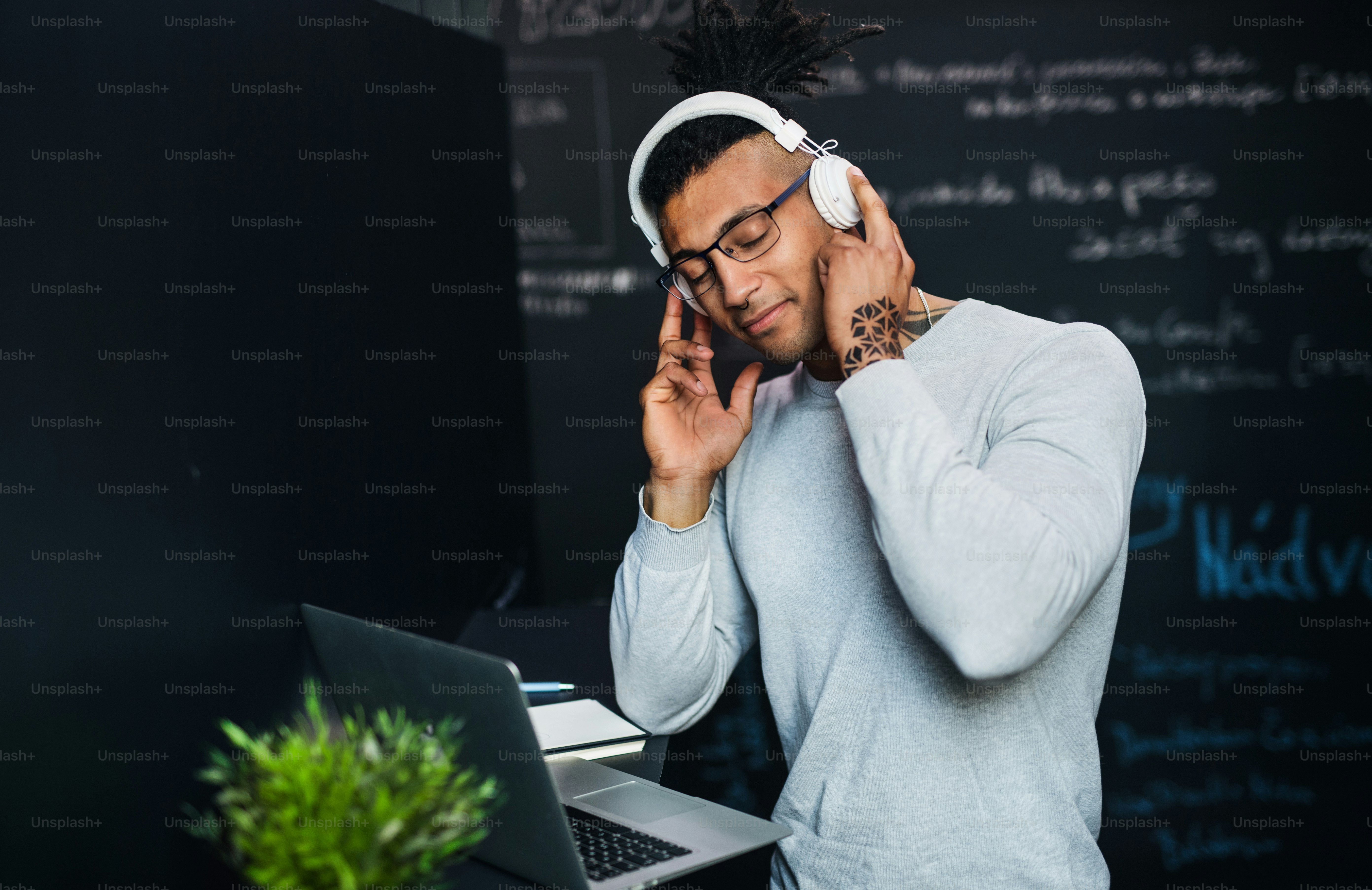 A young businessman with headphones in office, listening to music ...