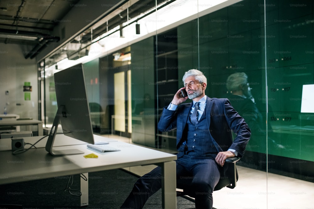 A portrait of mature businessman with smartphone in an office, making phone call.