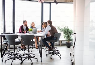 Un groupe de jeunes gens d’affaires assis dans un bureau, en réunion.