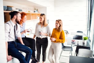 Un grupo de jóvenes empresarios en la pausa para el café en la cocina de la oficina, hablando.