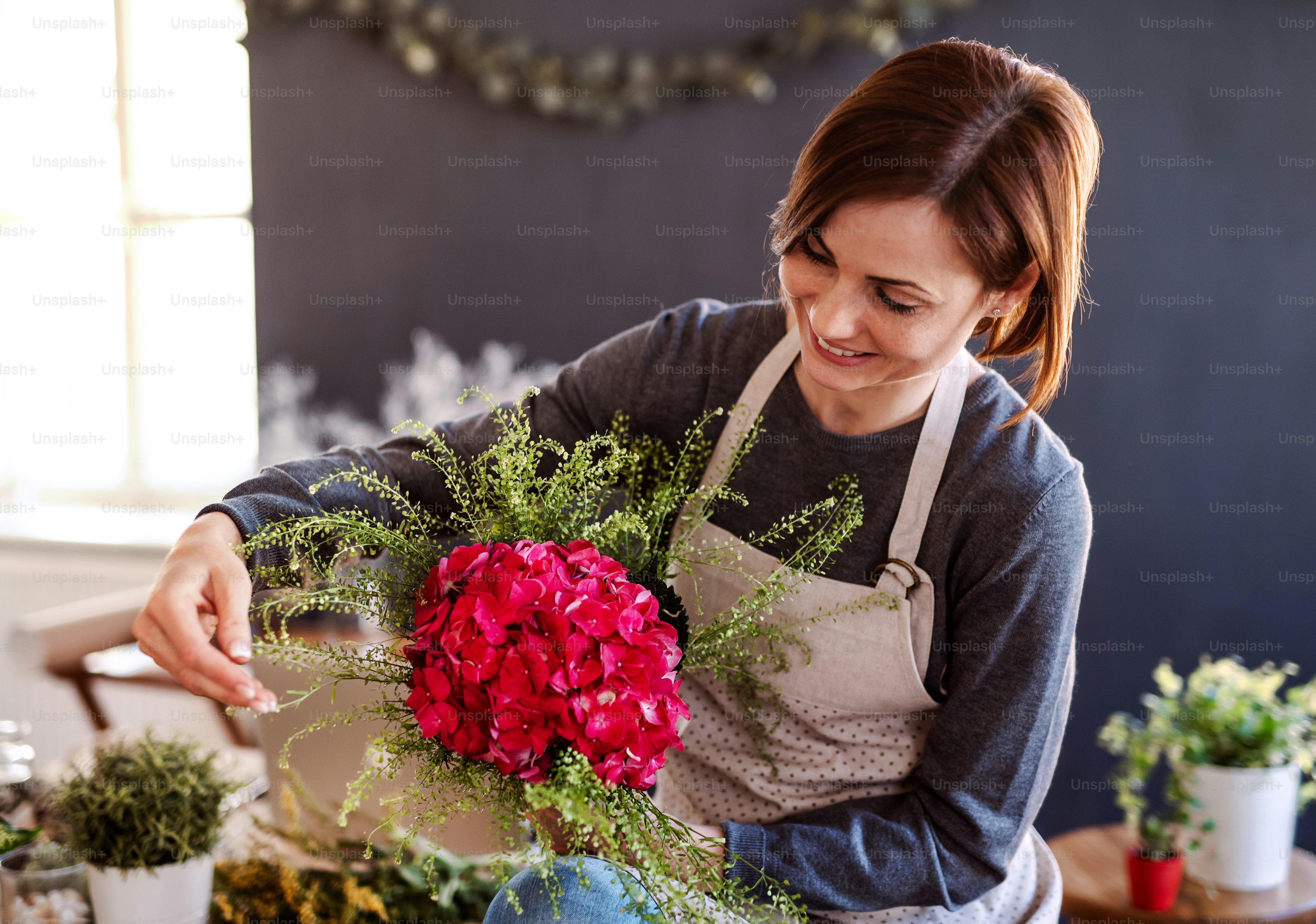 Eine junge kreative Frau arrangiert Blumen in einem Blumenladen. Ein Startup des Floristengeschäfts.