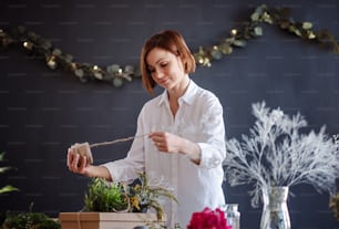 Eine junge kreative Frau arrangiert Blumen in einem Blumenladen. Ein Startup des Floristengeschäfts.