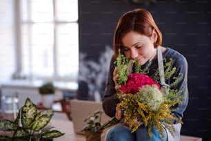 Uma jovem mulher criativa organizando flores em uma floricultura. Uma startup de negócios de floristas.