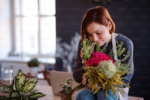 Una giovane donna creativa che organizza fiori in un negozio di fiori. Una startup di attività di fiorista.