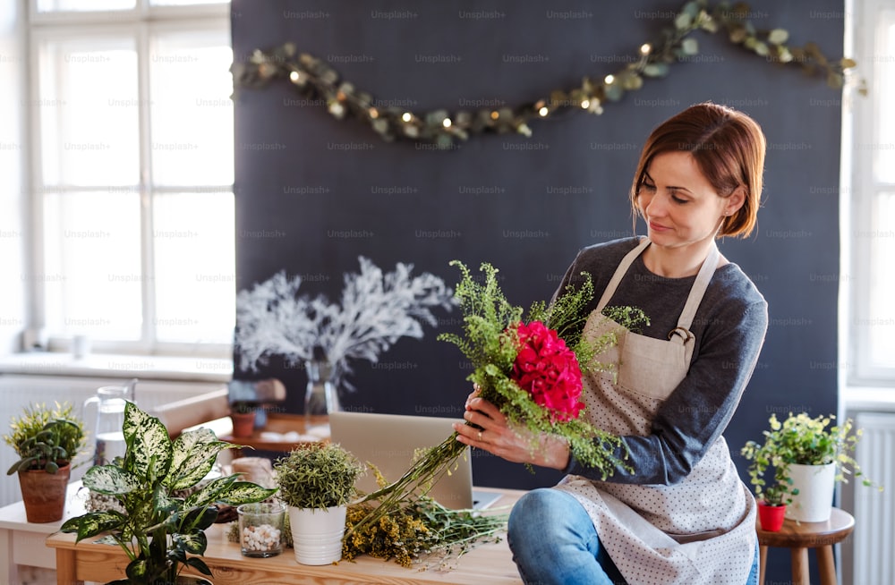 Uma jovem mulher criativa organizando flores em uma floricultura. Uma startup de negócios de floristas.