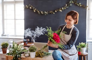 A young creative woman arranging flowers in a flower shop. A startup of florist business.