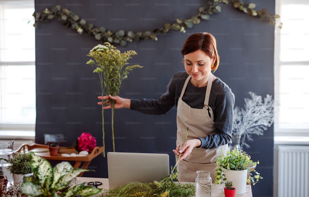 Una joven creativa arreglando flores en una floristería. Una startup de negocio de floristería.