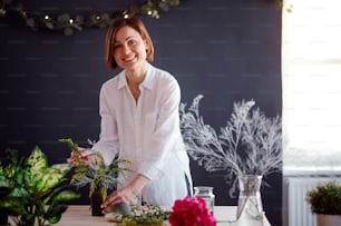 Eine junge kreative Frau arrangiert Blumen in einem Blumenladen. Ein Startup des Floristengeschäfts.