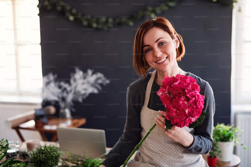 Una joven creativa arreglando flores en una floristería. Una startup de negocio de floristería.