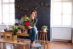 A young creative woman arranging flowers in a flower shop. A startup of florist business.