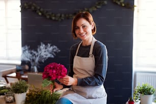 A young creative woman arranging flowers in a flower shop. A startup of florist business.