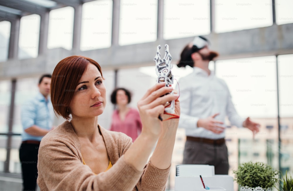 A young businesswoman or scientist with robotic hand standing in office, working.