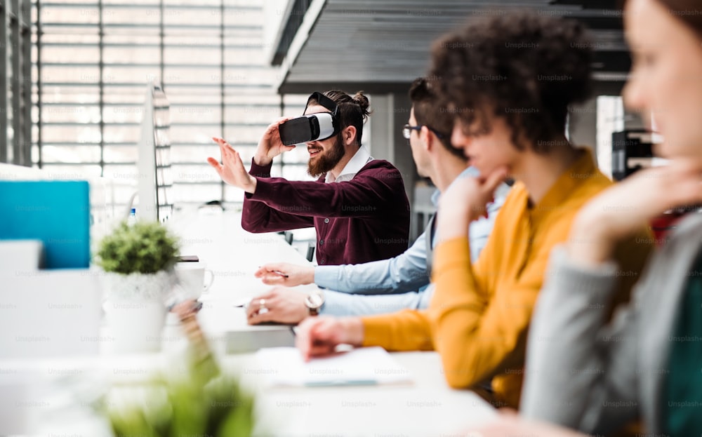 컴퓨터와 VR 고글을 착용한 젊은 사업가들이 사무실에서 함께 일하고 있다. 복사 공간.
