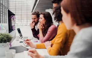 A group of young businesspeople working together in office, talking.