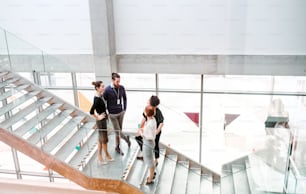 A group of young businesspeople standing on a staircase, talking.