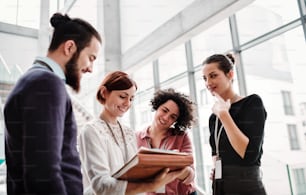 A group of young businesspeople standing near a staircase, talking.