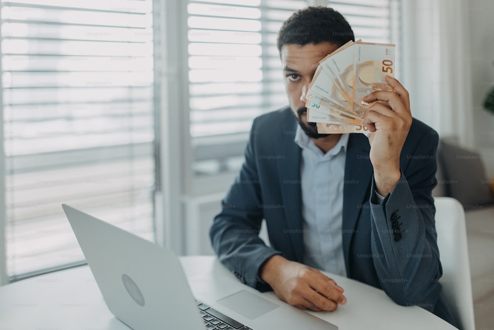 Un hombre de negocios deprimido contando dinero en euros trabajando en la computadora en el escritorio de la oficina, concepto de inflación.