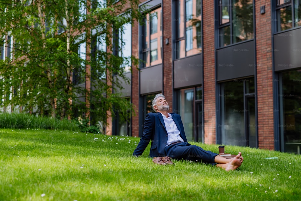 Un hombre de negocios maduro descansando y sentado descalzo en el parque, sintiéndose libre, escapando del trabajo, concepto de equilibrio entre la vida laboral y personal.
