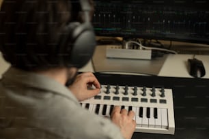 a person sitting at a desk with a keyboard and headphones