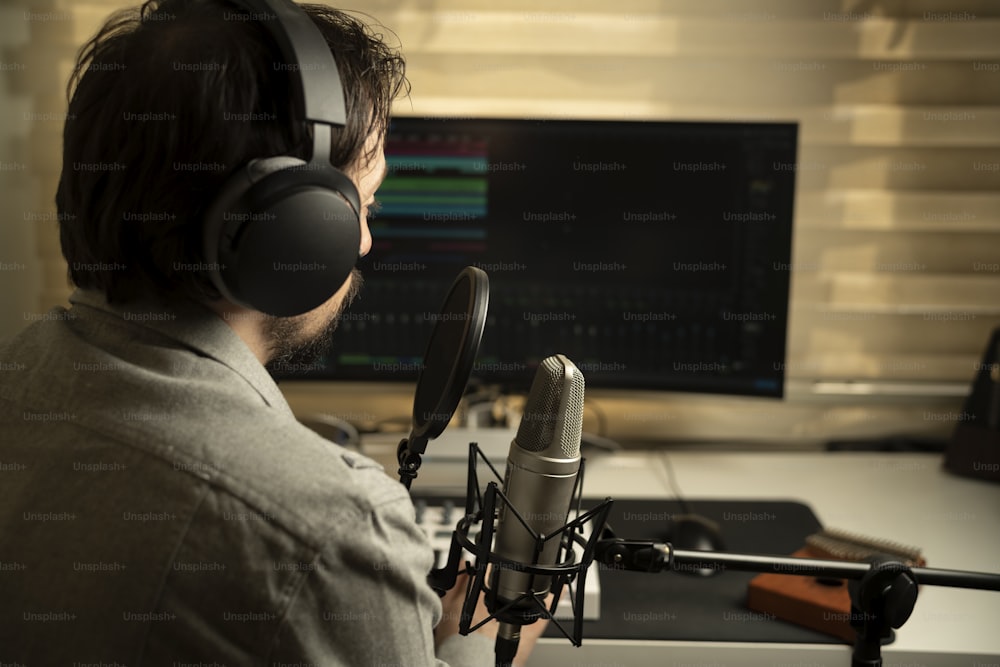 a man wearing headphones sitting in front of a microphone