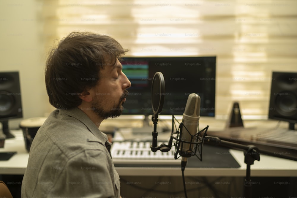 Un hombre sentado frente a un micrófono en un estudio de grabación