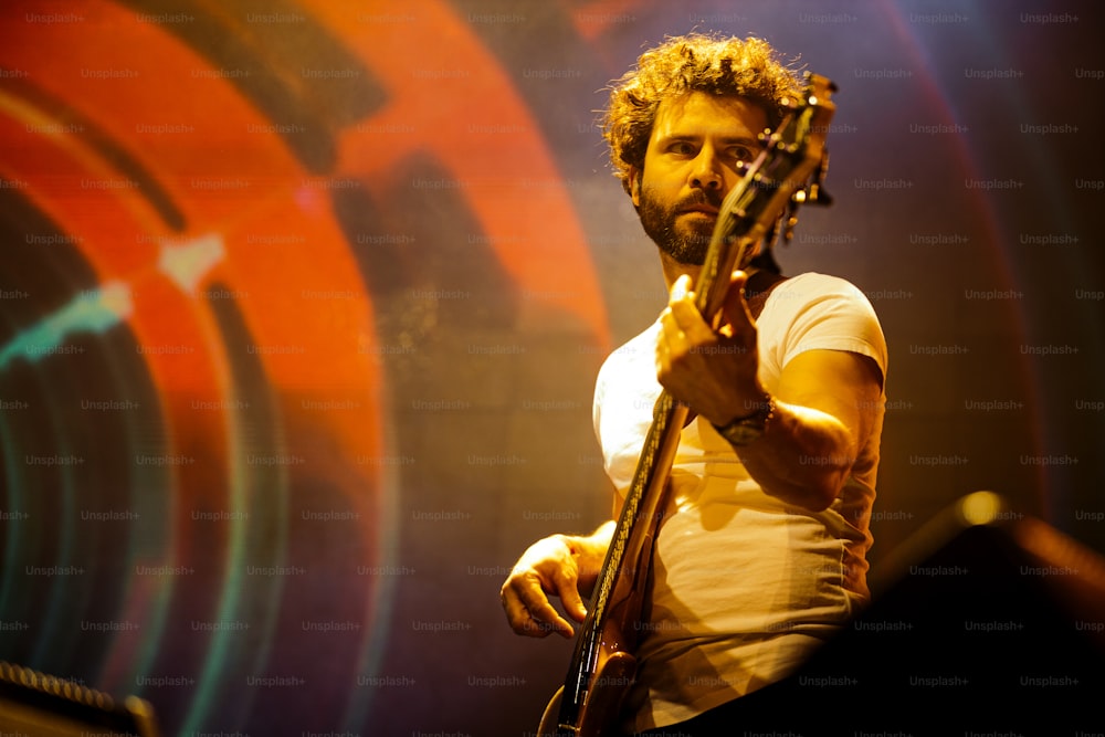 Un hombre sosteniendo una guitarra mientras está de pie en un escenario