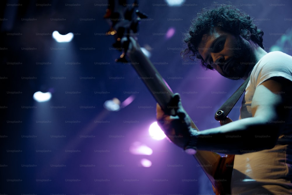 Un hombre tocando una guitarra en el escenario en un concierto
