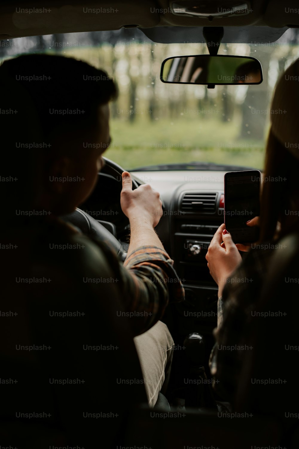 a man and a woman sitting in a car looking at a cell phone