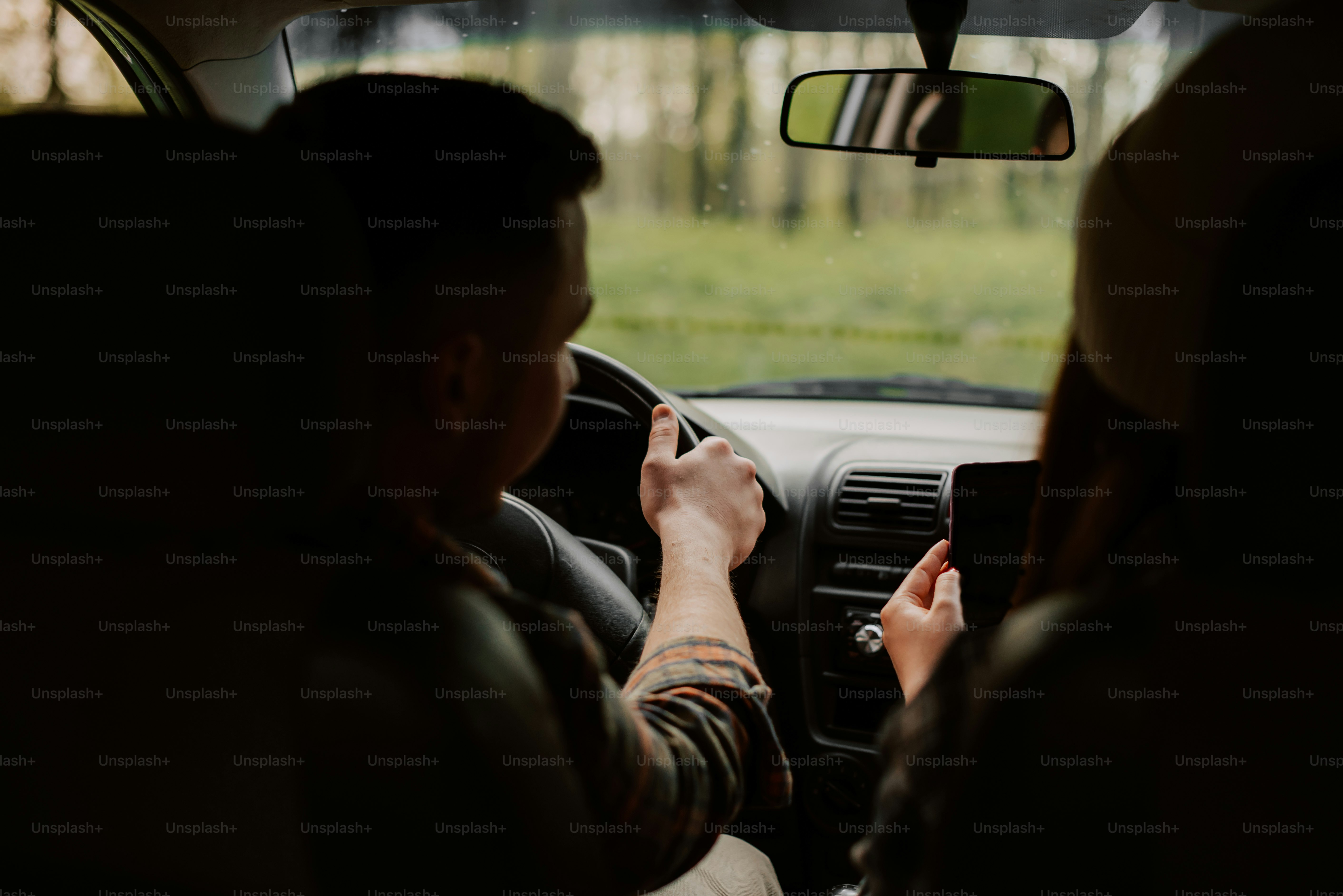 a man driving a car while holding a cell phone