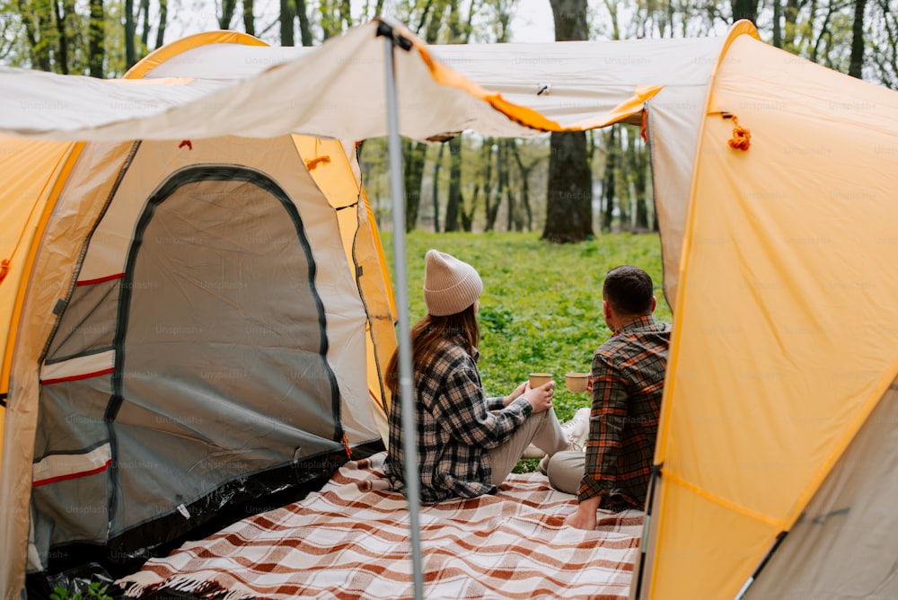 um par de pessoas sentadas ao lado de uma tenda