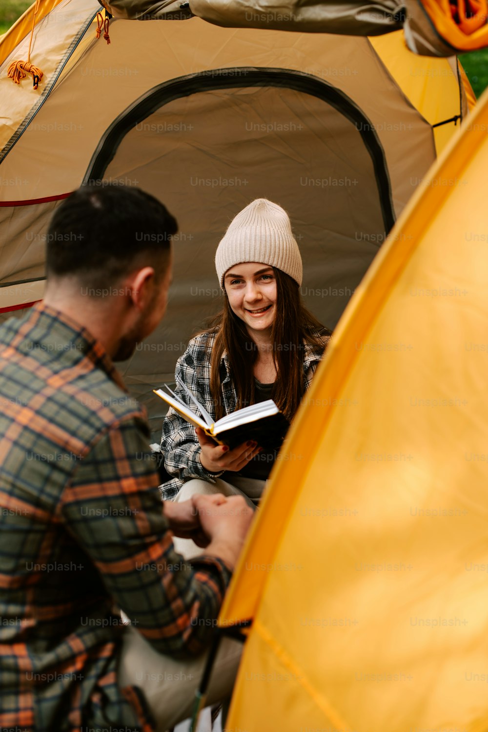 a man reading a book to a woman in a tent