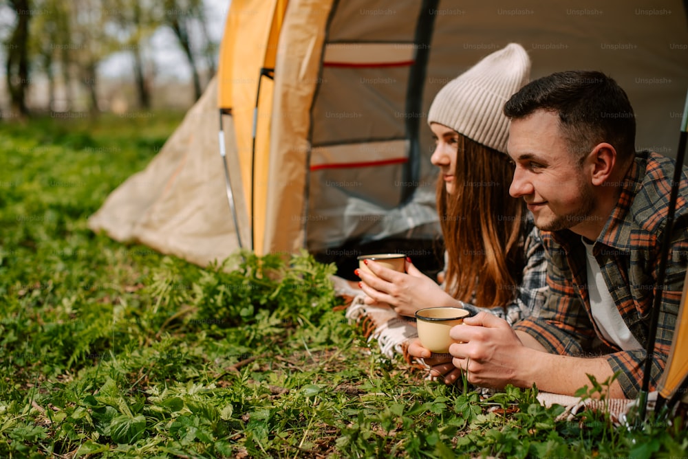 a man and a woman sitting in a tent with a cup of coffee
