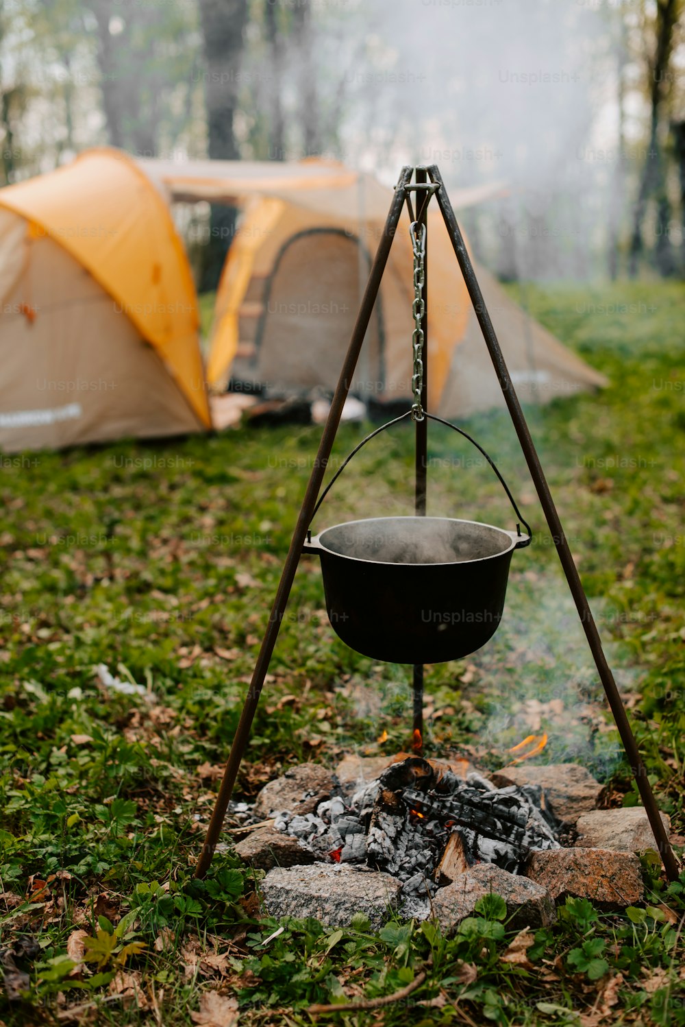 a pot on a stand next to a campfire